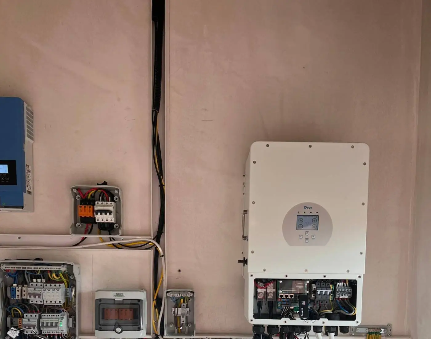 Instalacja elektryczna: falownik i skrzynki z przewodami na ścianie.